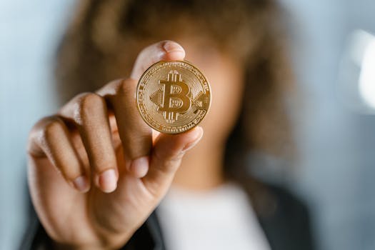 Close-up of a person holding a Bitcoin, symbolizing cryptocurrency and digital finance.