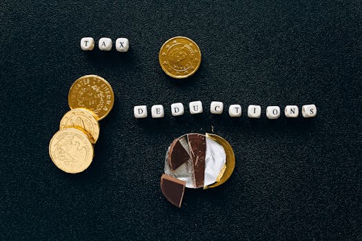 Creative concept of tax deductions using chocolate coins and letter tiles on a black background.