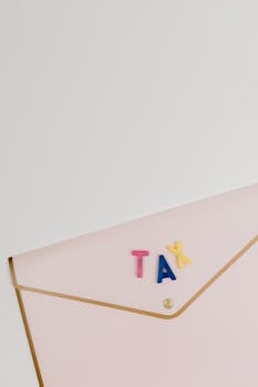 Pink envelope with TAX letters arranged on top, symbolizing tax-related themes.